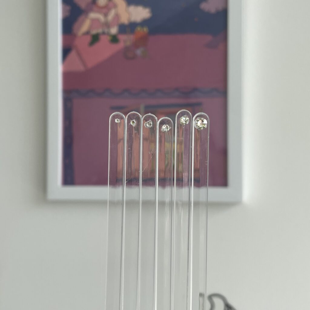 crystal try on sticks to use during your appointment that you book, in front of a purple tooth fairy picture in white frame
